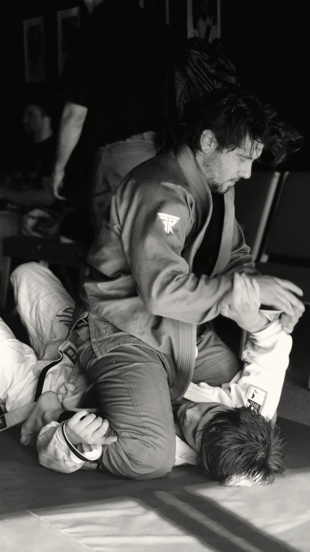 Elijah in a gi, training jiu-jitsu on the mat, in black and white