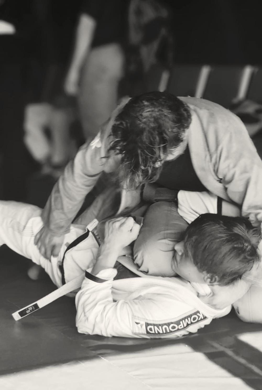 Two people grappling in a jiu-jitsu class, in black and white