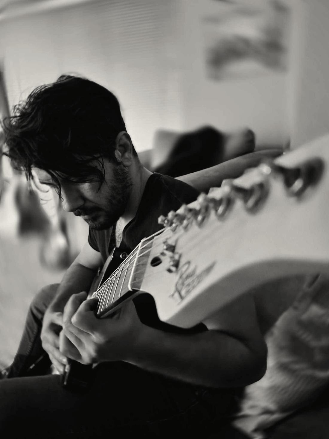 Elijah playing an electric guitar, in black and white